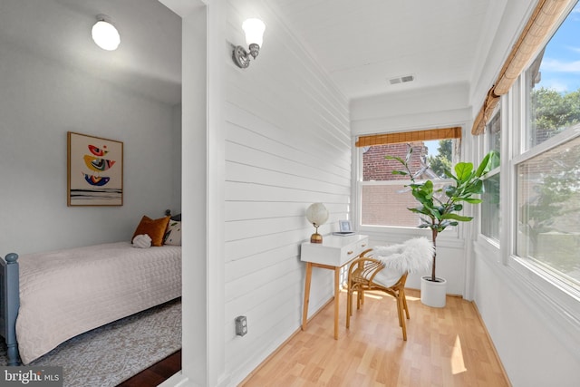 bedroom with wood walls and hardwood / wood-style flooring