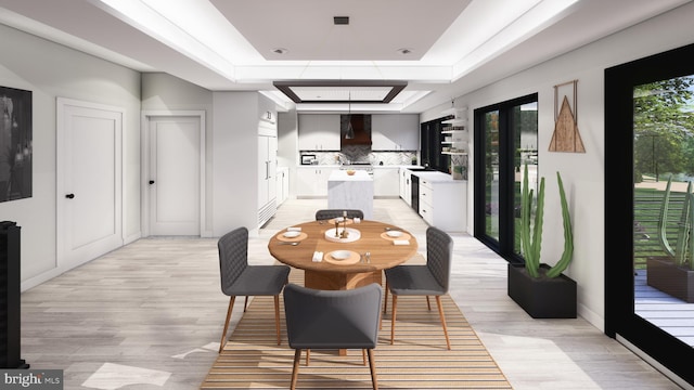 dining space with french doors, a tray ceiling, and light hardwood / wood-style flooring