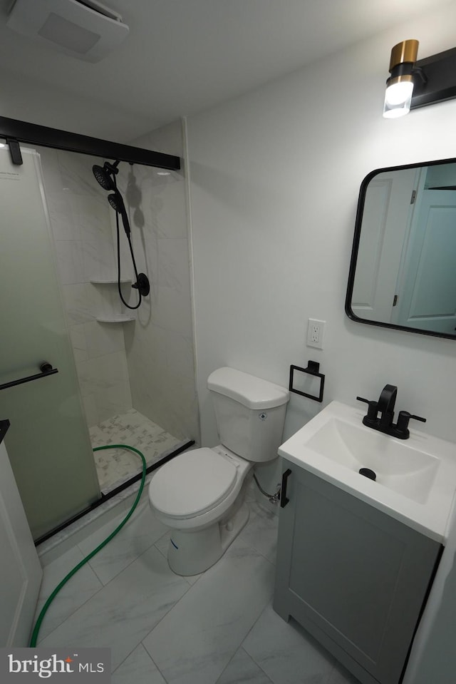 bathroom featuring vanity, a shower with door, and toilet