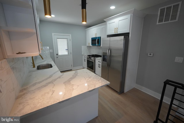 kitchen featuring sink, appliances with stainless steel finishes, white cabinetry, backsplash, and light stone counters