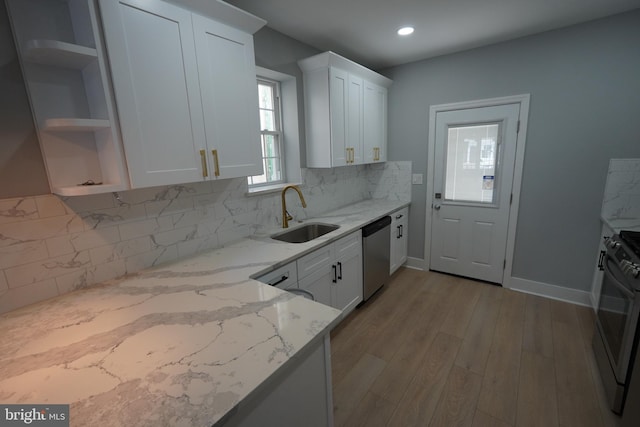 kitchen featuring sink, white cabinetry, tasteful backsplash, light stone counters, and appliances with stainless steel finishes