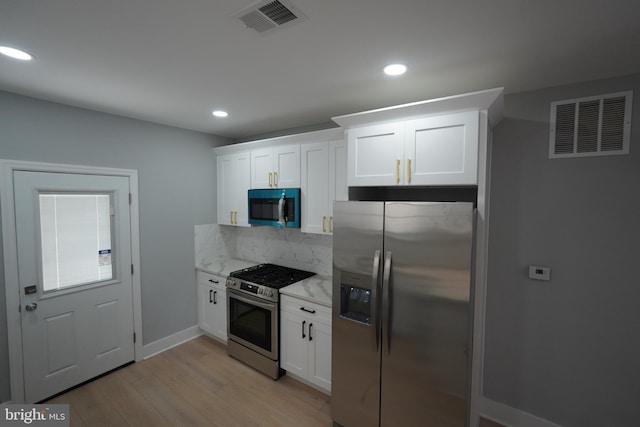 kitchen featuring light stone countertops, appliances with stainless steel finishes, white cabinets, and light hardwood / wood-style floors