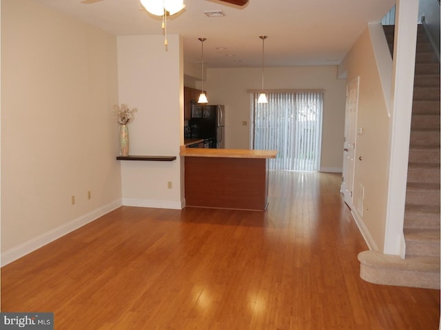 kitchen featuring ceiling fan, kitchen peninsula, stainless steel fridge, pendant lighting, and hardwood / wood-style flooring