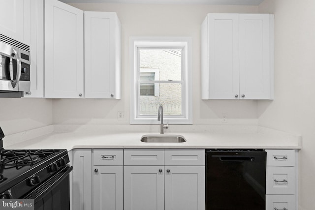 kitchen with black appliances, white cabinets, and sink