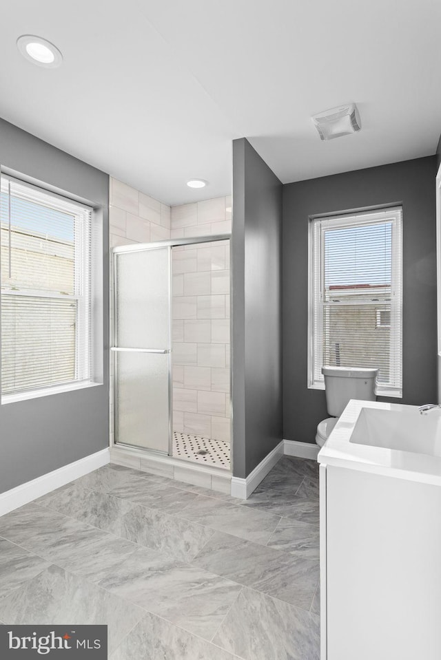 bathroom with toilet, an enclosed shower, plenty of natural light, and vanity