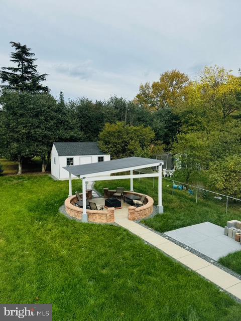 view of community featuring a lawn, a storage unit, a patio, and an outdoor fire pit