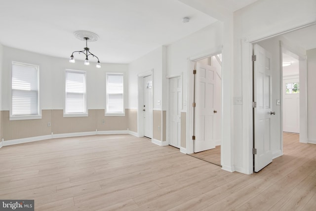 empty room featuring light wood-type flooring and an inviting chandelier