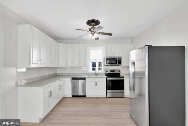 kitchen featuring white cabinets, ceiling fan, sink, and stainless steel appliances