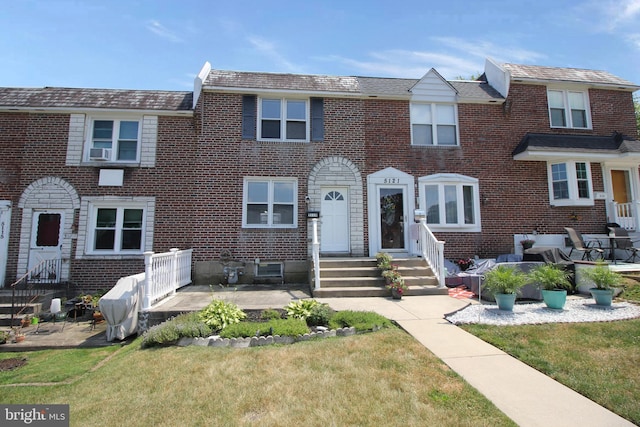 multi unit property featuring a front lawn and brick siding