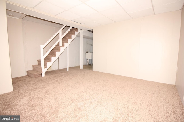 finished below grade area featuring carpet flooring, stairway, and a drop ceiling