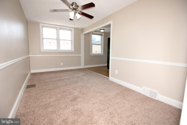 unfurnished room with visible vents, baseboards, carpet, and a ceiling fan