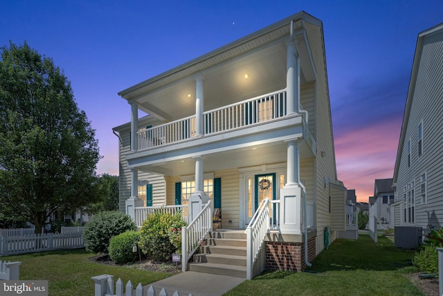 view of front facade featuring covered porch, a yard, cooling unit, and a balcony