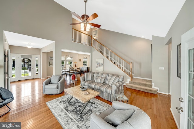 living room featuring ceiling fan, light hardwood / wood-style flooring, a high ceiling, and french doors