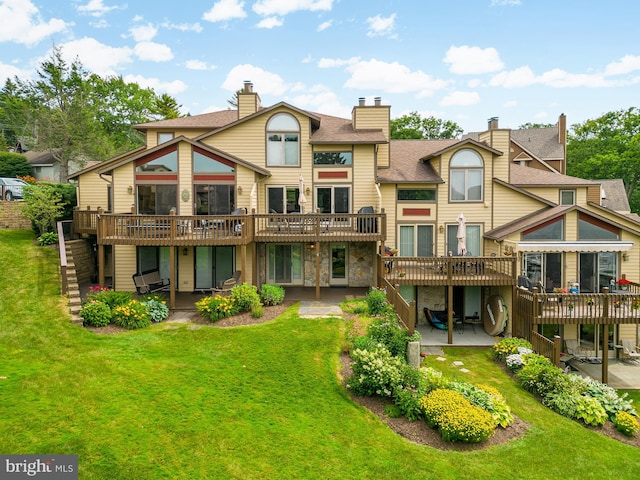 back of property with a lawn, a wooden deck, and a patio