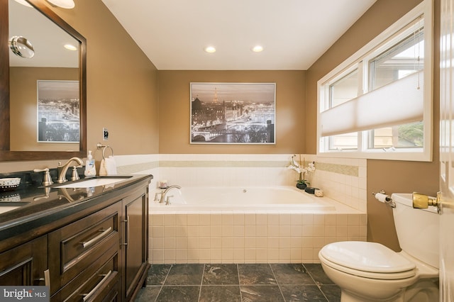 bathroom featuring vanity, toilet, and tiled bath