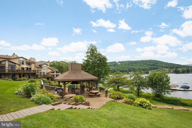 view of home's community with a deck with water view, a gazebo, and a lawn