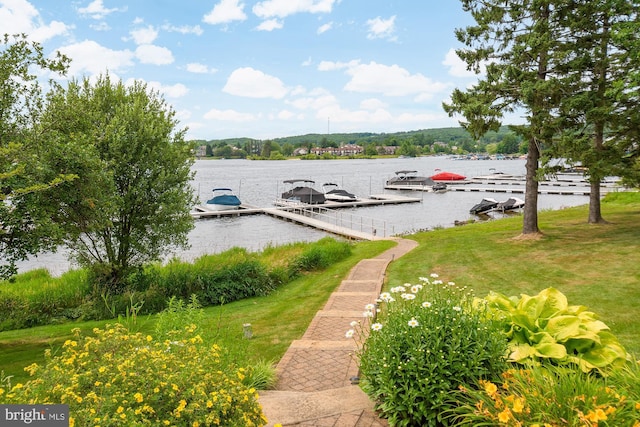 view of dock with a lawn and a water view