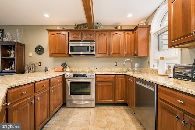 kitchen featuring beam ceiling, light stone countertops, sink, and appliances with stainless steel finishes