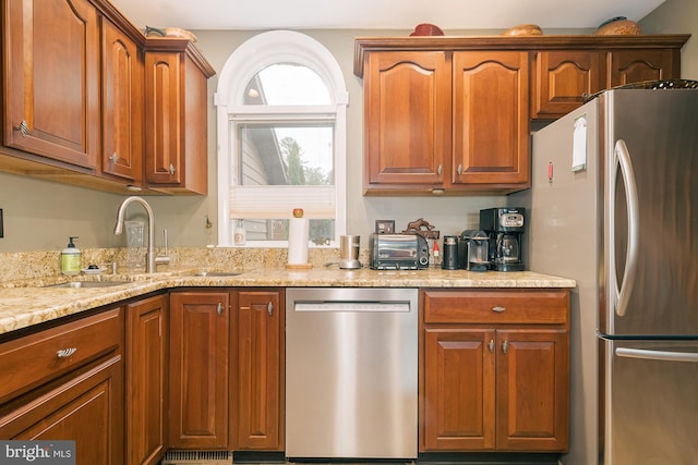 kitchen featuring sink, light stone counters, and stainless steel appliances