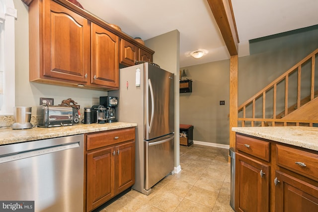 kitchen featuring beamed ceiling, light stone counters, and stainless steel appliances