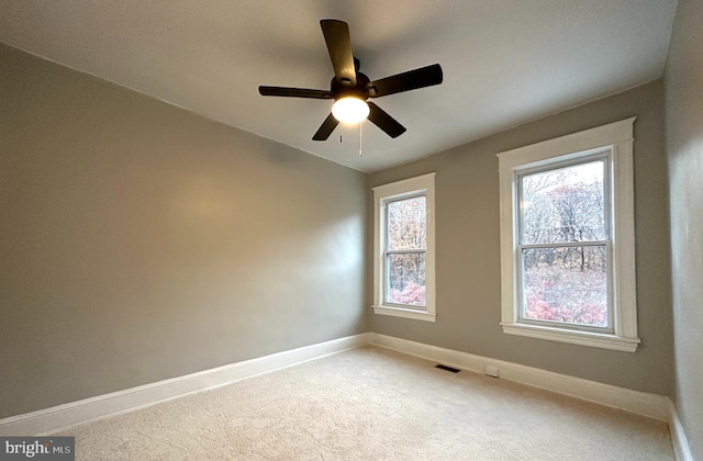 unfurnished room with ceiling fan and carpet