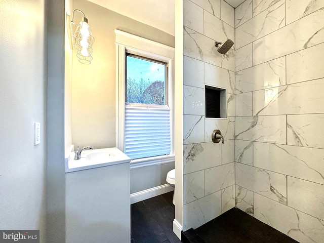 bathroom featuring vanity, a healthy amount of sunlight, toilet, and tiled shower