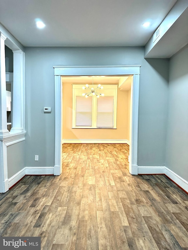 hall with a notable chandelier and wood-type flooring