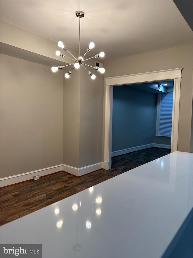 unfurnished dining area featuring dark hardwood / wood-style flooring and an inviting chandelier