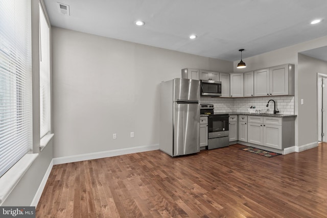 kitchen with sink, hanging light fixtures, dark hardwood / wood-style floors, appliances with stainless steel finishes, and tasteful backsplash