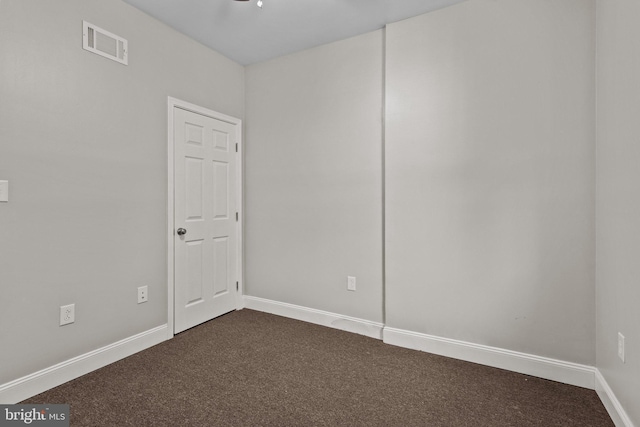 spare room featuring dark carpet