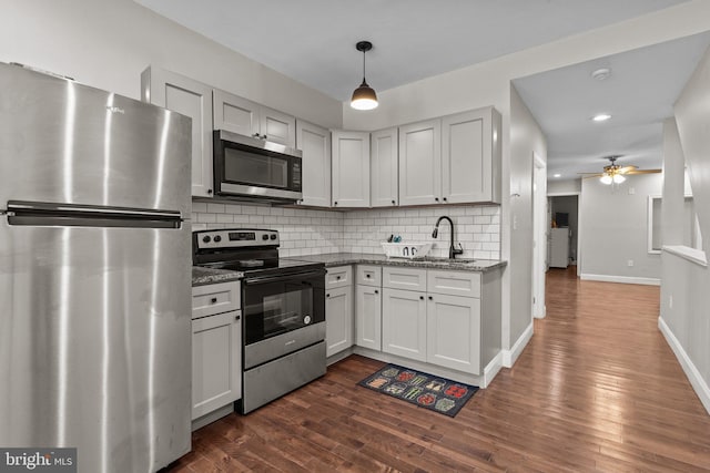 kitchen with ceiling fan, sink, stainless steel appliances, backsplash, and dark stone counters