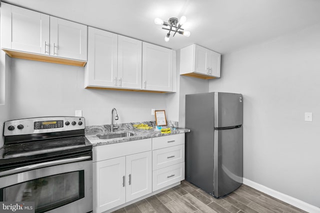 kitchen with white cabinets, light stone counters, sink, and appliances with stainless steel finishes