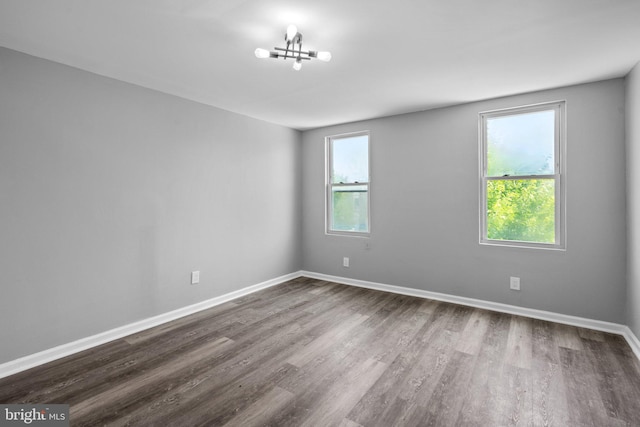 empty room featuring dark wood-type flooring and an inviting chandelier