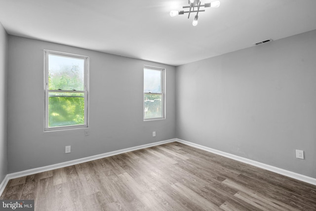 spare room with a chandelier and hardwood / wood-style flooring