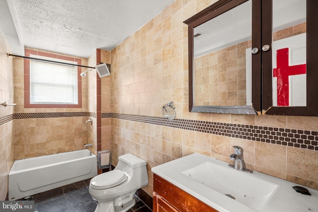 full bathroom with vanity, tiled shower / bath combo, toilet, a textured ceiling, and tile walls