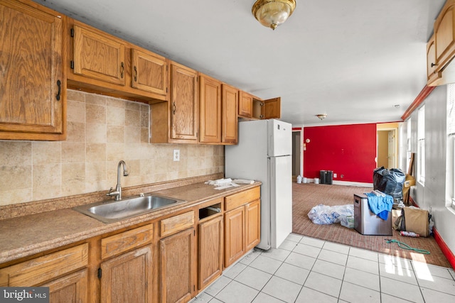 kitchen with light tile patterned floors, white refrigerator, and sink