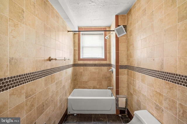 bathroom featuring a textured ceiling, toilet, and tile walls