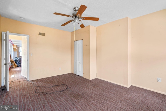 carpeted empty room with ceiling fan and a textured ceiling