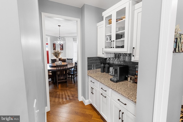 bar with white cabinetry, hanging light fixtures, light stone counters, decorative backsplash, and hardwood / wood-style flooring