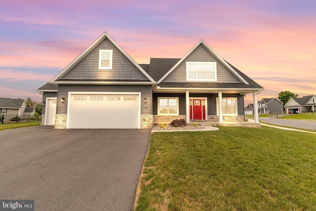 craftsman inspired home with covered porch, a garage, and a yard