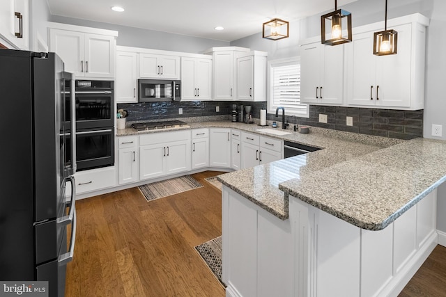 kitchen with kitchen peninsula, appliances with stainless steel finishes, sink, decorative light fixtures, and white cabinetry