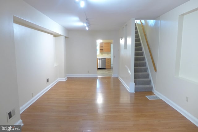 basement with rail lighting and light wood-type flooring