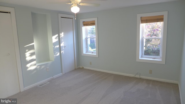 spare room with ceiling fan, plenty of natural light, and light carpet