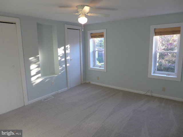 empty room with ceiling fan and light carpet