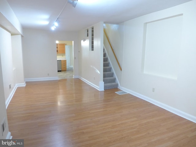 basement with track lighting and light hardwood / wood-style flooring