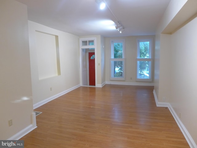 spare room featuring rail lighting and light hardwood / wood-style floors