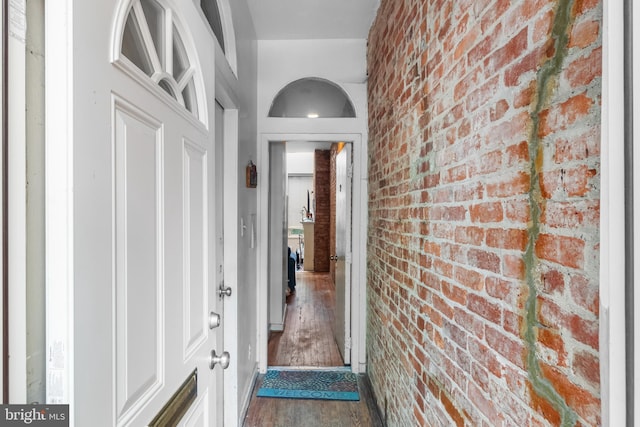 doorway to outside with brick wall and hardwood / wood-style floors