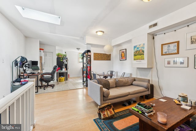 living room with a skylight and light hardwood / wood-style flooring