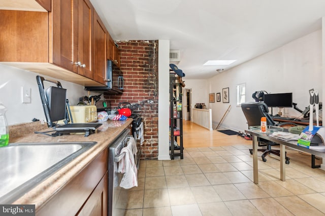 kitchen with a skylight, sink, stainless steel dishwasher, and brick wall