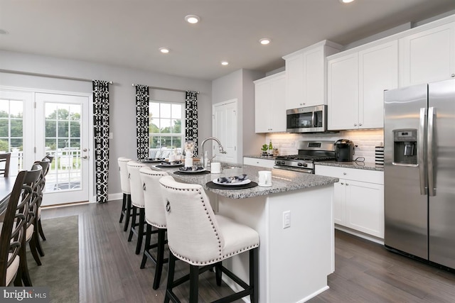 kitchen featuring white cabinets, appliances with stainless steel finishes, dark hardwood / wood-style flooring, and a center island with sink